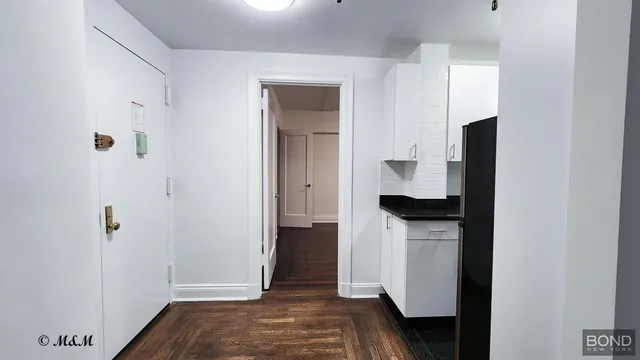 a view of hallway with walk in closet and wooden floor