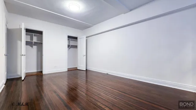 a view of an empty room with wooden floor and closet