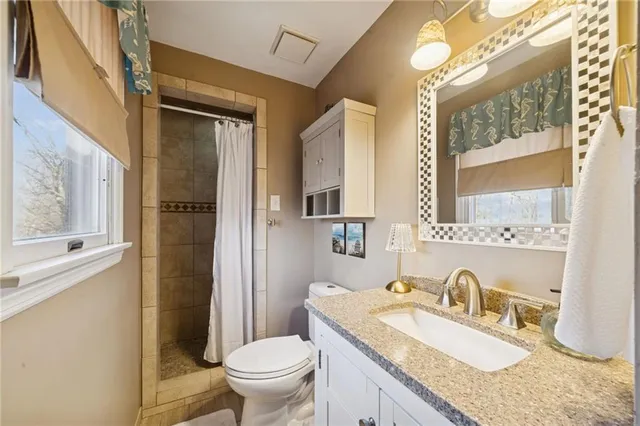 a bathroom with a granite countertop sink mirror vanity and toilet