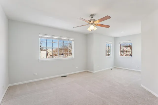 an empty room with windows and fan