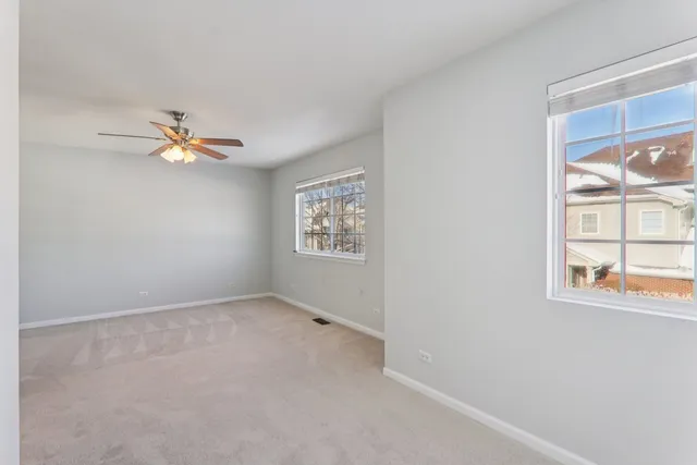 an empty room with windows and fan view