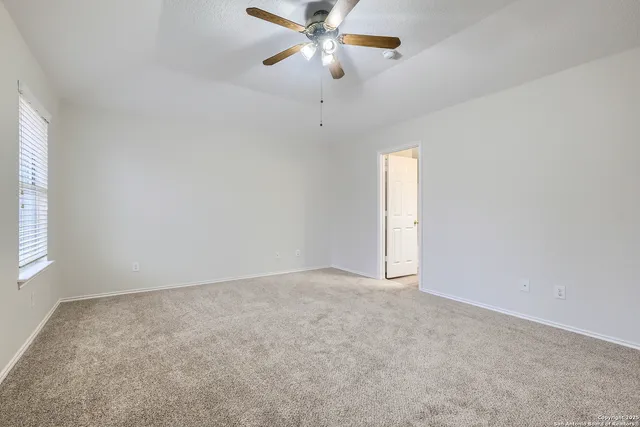 an empty room with a window and a fan