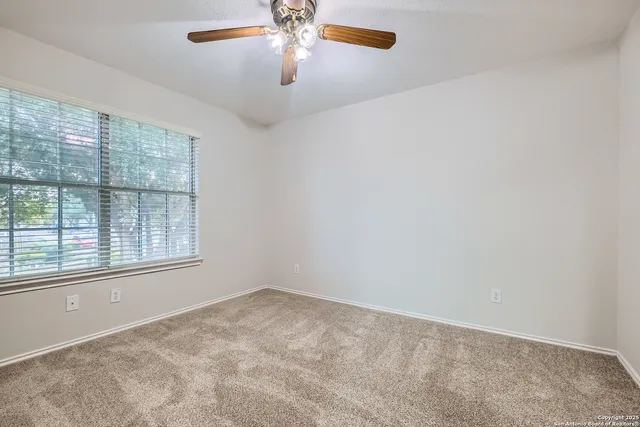 an empty room with windows and fan