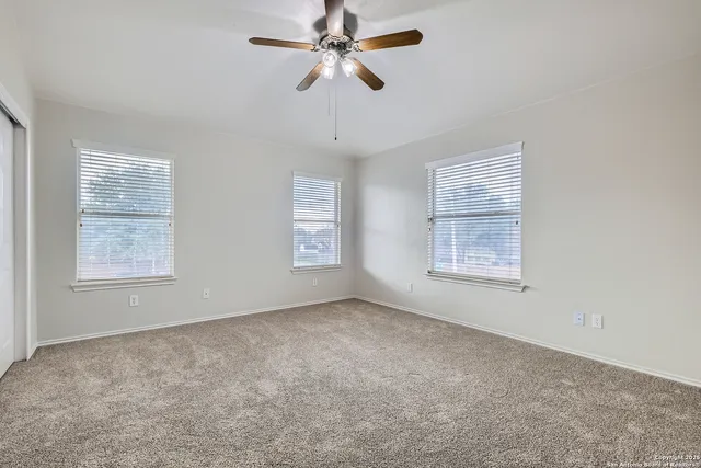 an empty room with windows and fan