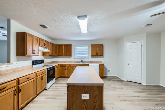 a kitchen with stainless steel appliances granite countertop a sink a stove top oven a counter space and cabinets
