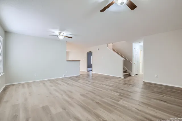 wooden floor in an empty room with a chandelier fan