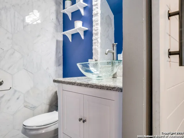a bathroom with a granite countertop sink a toilet and a mirror