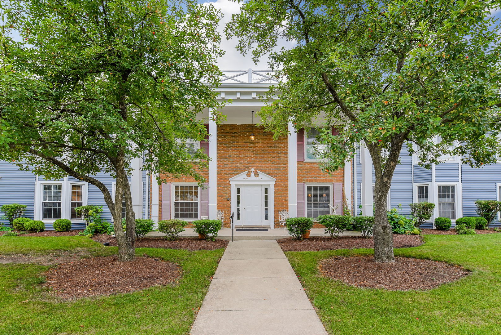 a front view of a house with a garden and trees