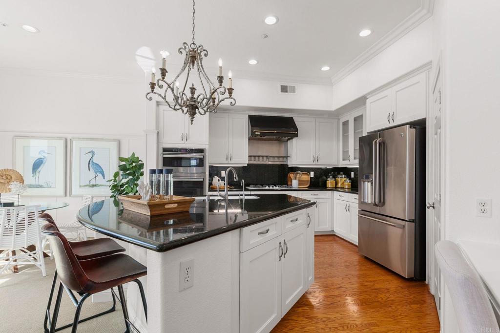 2738 MacKinnon Ranch Road Cardiff-by-the-Sea, CA 92007 - Photo 14 of 58 a kitchen with stainless steel appliances granite countertop a refrigerator a sink dishwasher a stove and a dining table with wooden floor