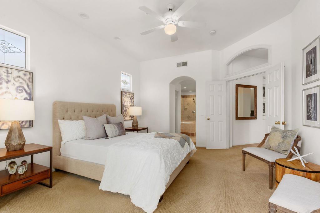 2738 MacKinnon Ranch Road Cardiff-by-the-Sea, CA 92007 - Photo 27 of 58 a spacious bedroom with a bed and a chandelier