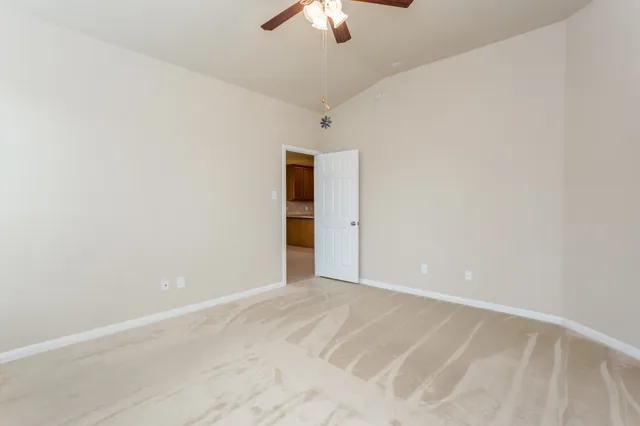 a view of an empty room with chandelier fan