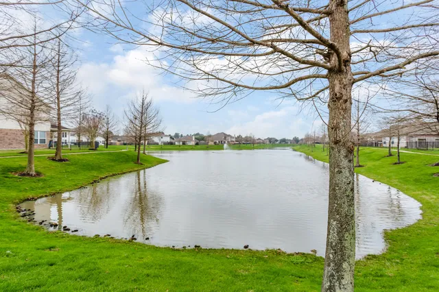a view of a lake with a yard and large trees