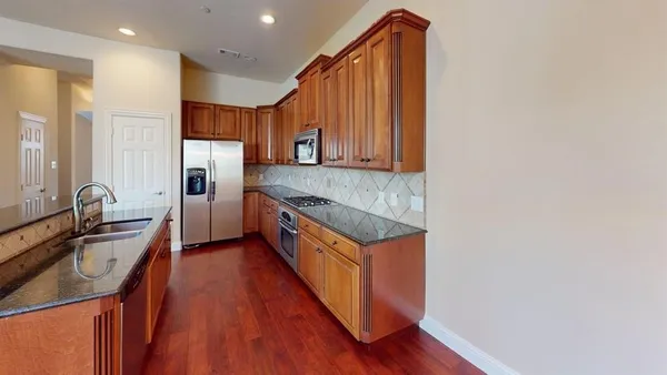 a kitchen with stainless steel appliances granite countertop a stove a sink and a refrigerator
