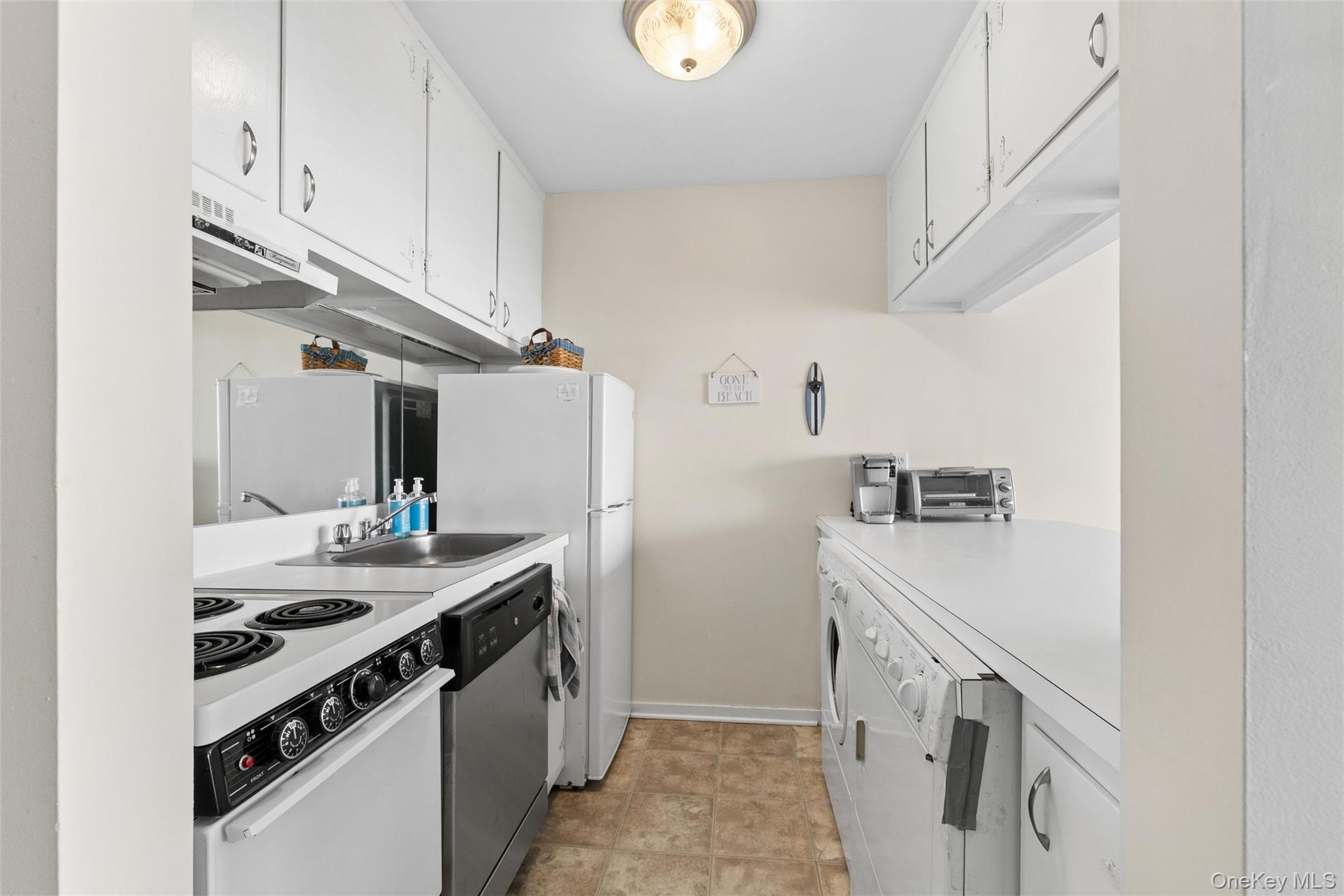 274 Dune Road, Unit 9 Westhampton Beach, NY 11978 - Photo 6 of 13 a kitchen with stainless steel appliances granite countertop a sink stove and refrigerator