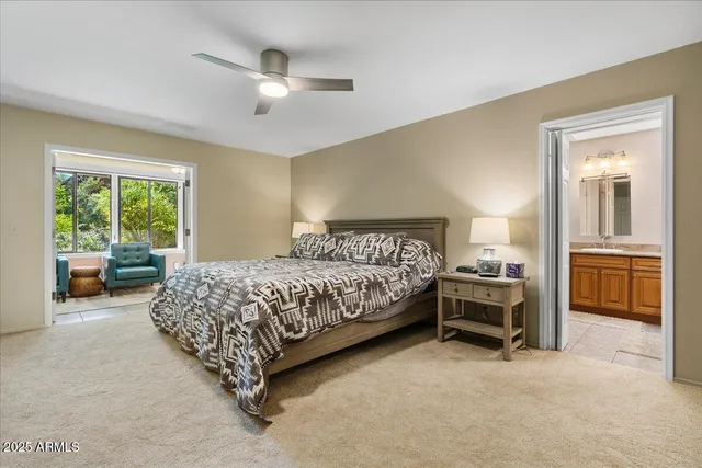 a bedroom with a large bed and a chandelier fan