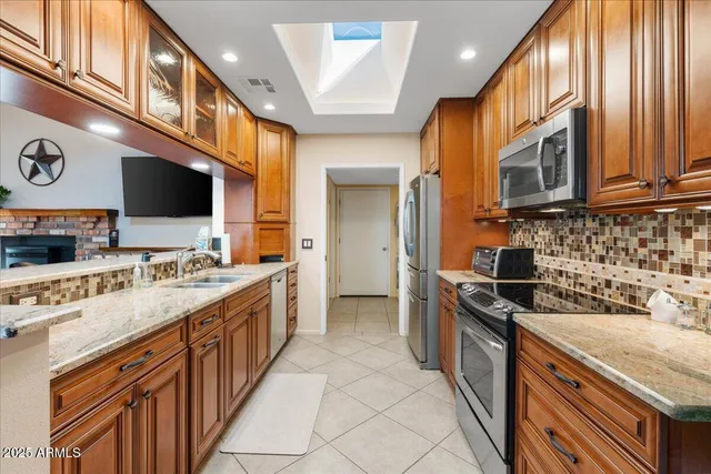 a kitchen with stainless steel appliances granite countertop a stove a sink and a microwave