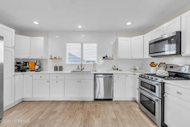 a kitchen with white cabinets sink and stainless steel appliances