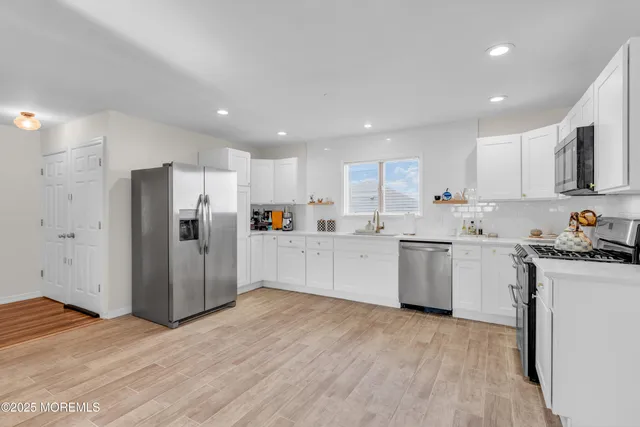a kitchen with refrigerator a microwave and white cabinets
