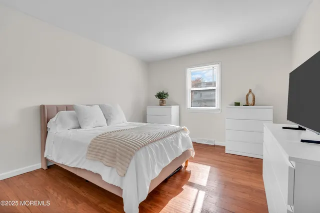 a bedroom with a bed and a flat tv screen on a dresser