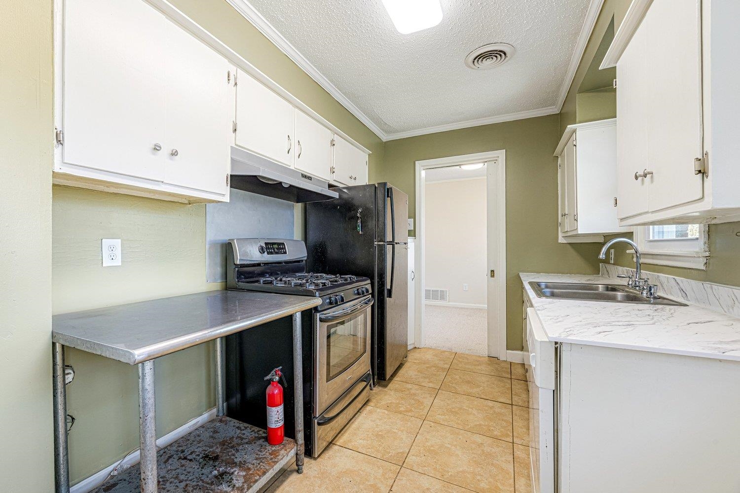 4490 Garnett Road Memphis, TN 38117 - Photo 11 of 18 Kitchen with a textured ceiling, stainless steel appliances, light countertops, white cabinetry, and crown molding