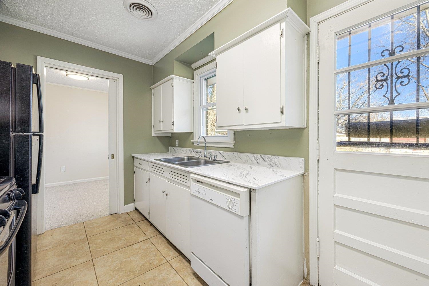 4490 Garnett Road Memphis, TN 38117 - Photo 12 of 18 Kitchen with dishwasher, light countertops, white cabinets, a textured ceiling, and crown molding
