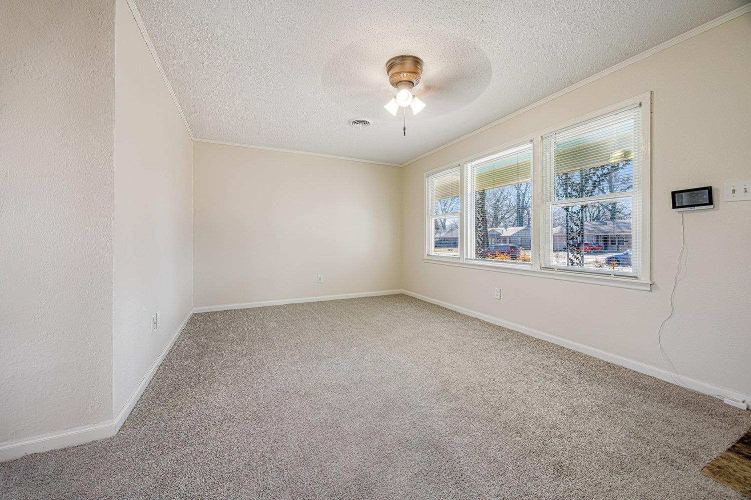 4490 Garnett Road Memphis, TN 38117 - Photo 7 of 18 Spare room featuring ornamental molding, light carpet, a textured ceiling, and a ceiling fan