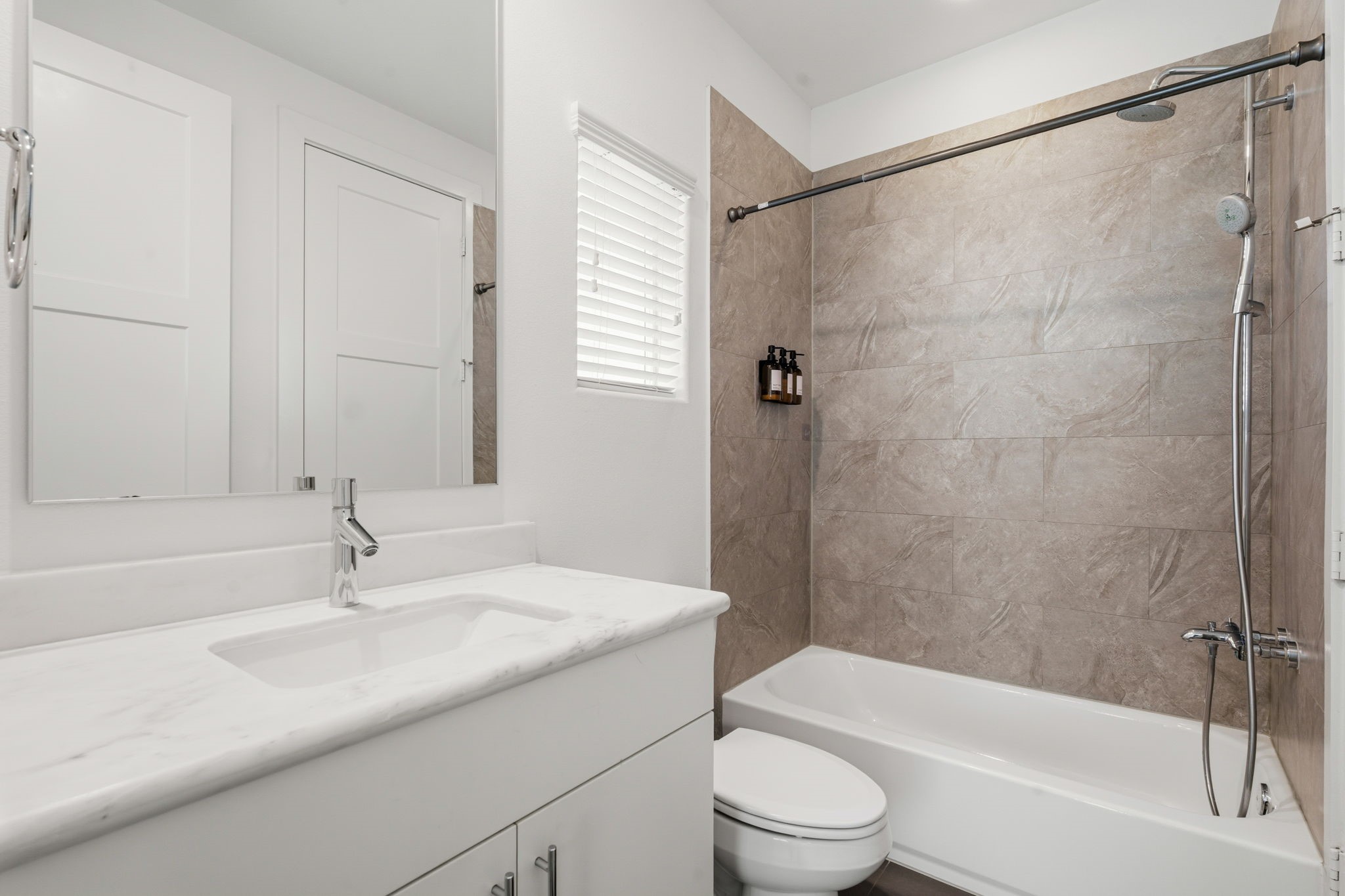 2624 Rusk Street Houston, TX 77003 - Photo 7 of 30 Elegant and modern bathroom featuring a sleek vanity, stylish tile walls, and a spacious tub-shower combination.