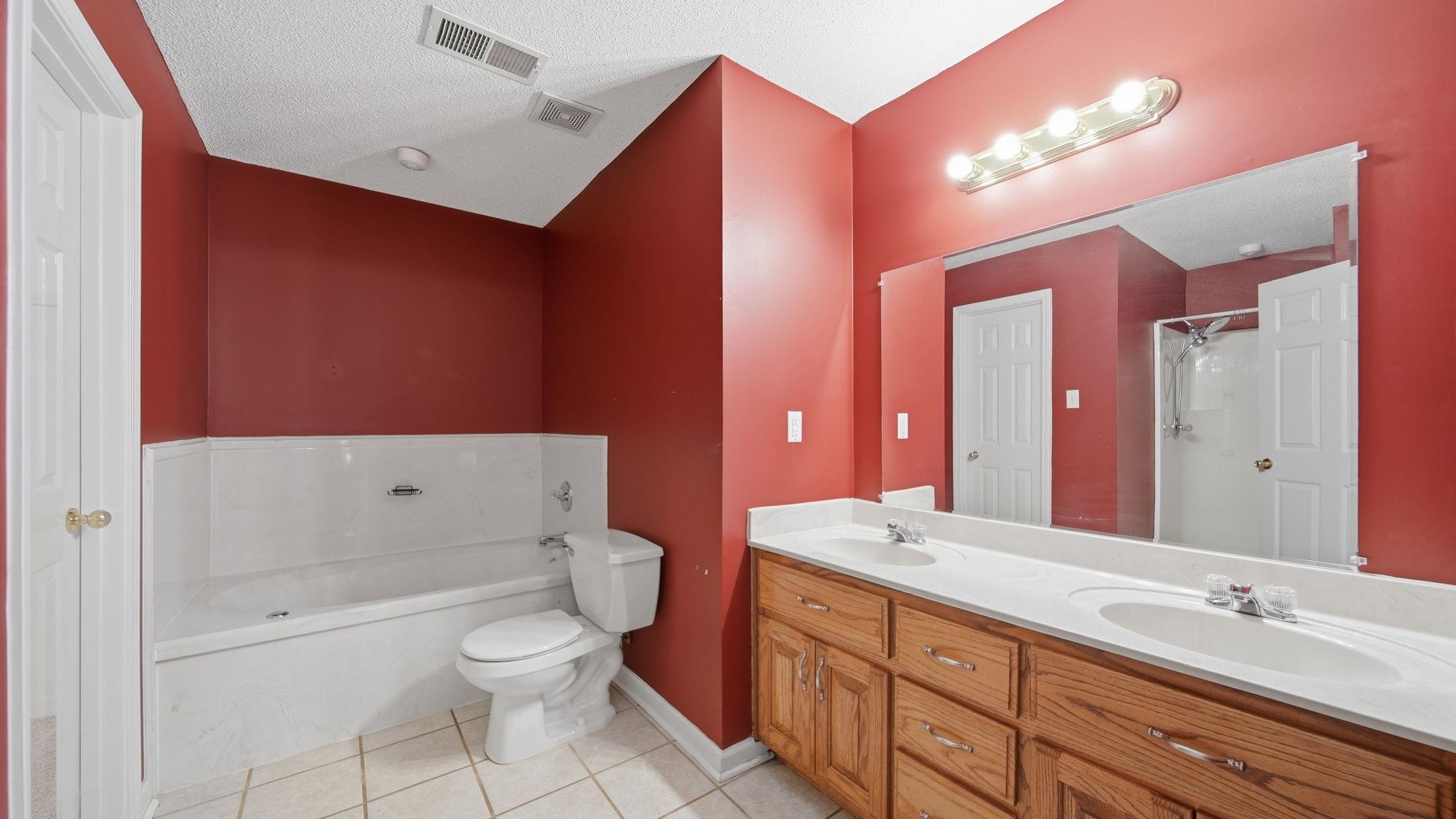 217 Rae Drive Munford, TN 38058 - Photo 20 of 40 Double vanity with light wood cabinetry, dual undermount sinks, and a full-width mirror jetted tub and separate shower.
