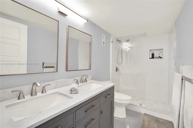 a bathroom with a double vanity sink toilet mirror and shower