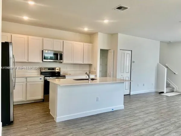 a kitchen with kitchen island a refrigerator sink and cabinets