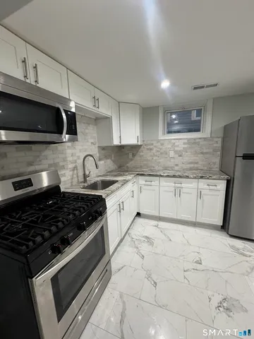 a kitchen with granite countertop a sink stove and cabinets