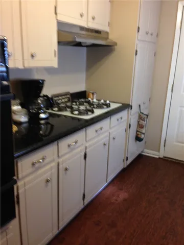 a kitchen with granite countertop white cabinets and black appliances