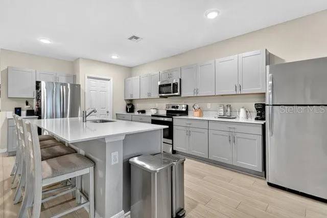 a kitchen with a refrigerator a white stove top oven and white cabinets with wooden floor