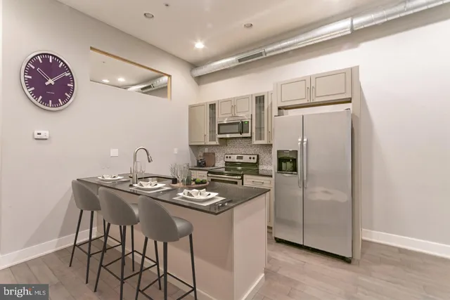 a kitchen with stainless steel appliances granite countertop a refrigerator a stove a sink a dining table and chairs