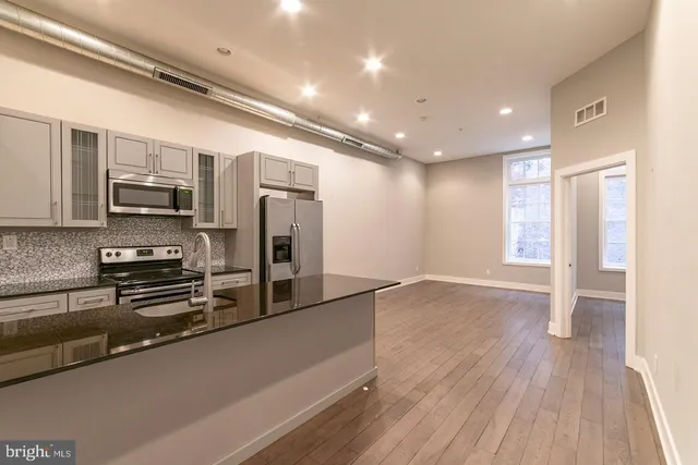 a view of kitchen with stainless steel appliances granite countertop a refrigerator and a stove top oven