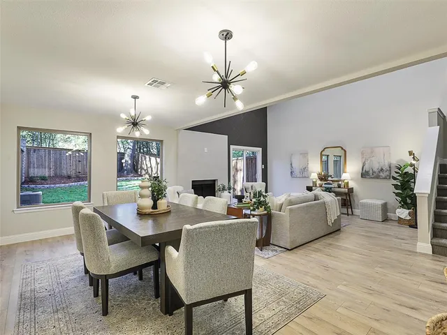 a dining room with wooden floor a chandelier a wooden table and chairs
