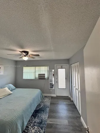 a spacious bedroom with a balcony outdoor seating and windows