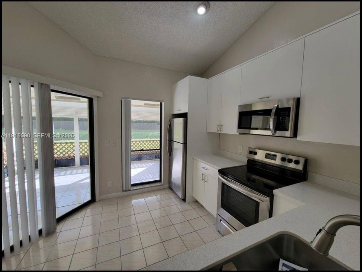 9336 Ketay Circle Boca Raton, FL 33428 - Photo 11 of 48 a kitchen with stainless steel appliances a stove a sink and a refrigerator