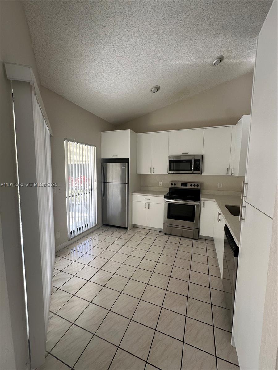 9336 Ketay Circle Boca Raton, FL 33428 - Photo 14 of 48 a kitchen with stainless steel appliances a refrigerator sink and cabinets