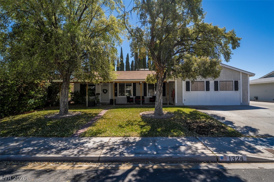 A welcoming facade with a covered porch framed by mature trees and a spacious driveway.
