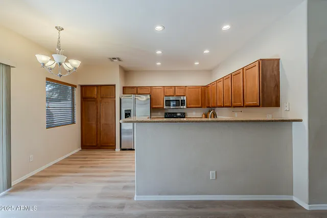 a view of a kitchen with stainless steel appliances granite countertop a refrigerator a stove a sink dishwasher and a wooden cabinets with wooden floor