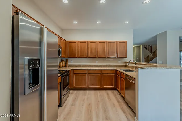 a kitchen with granite countertop a refrigerator and wooden cabinets