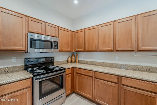 a kitchen with granite countertop a stove top oven microwave and cabinets
