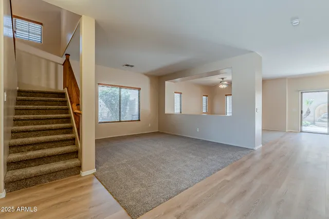 a view of an empty room with wooden floor and windows