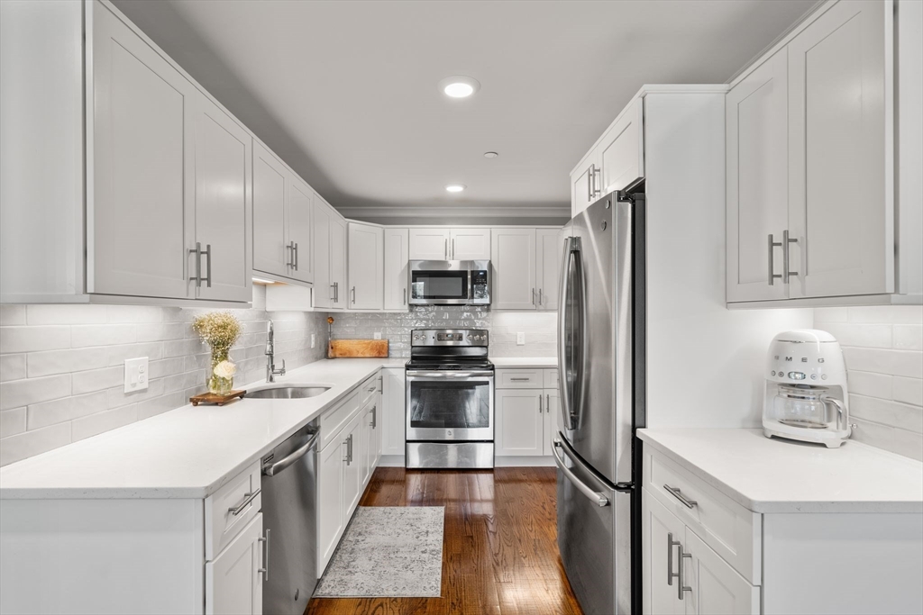 1789 Centre Street, Unit 401 Boston, MA 02132 - Photo 5 of 30 a kitchen with a refrigerator a sink and white cabinets