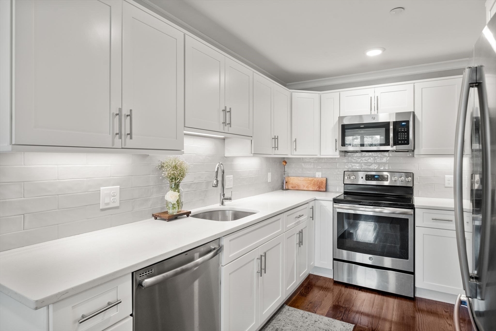 1789 Centre Street, Unit 401 Boston, MA 02132 - Photo 6 of 30 a kitchen with a sink stove and microwave