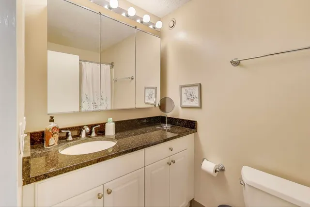 a bathroom with a granite countertop sink a mirror and a shower