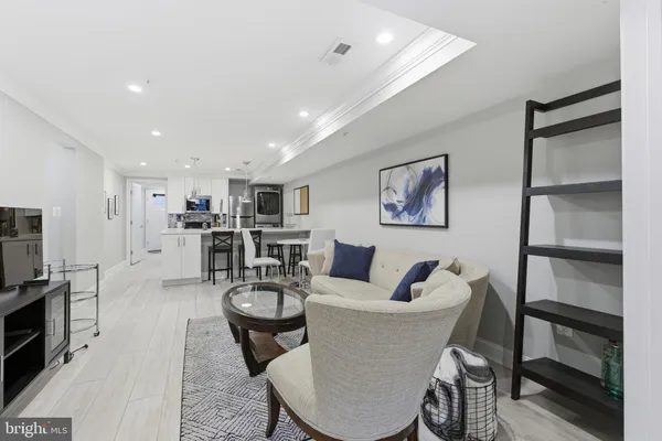 a living room with stainless steel appliances furniture a rug and a kitchen view