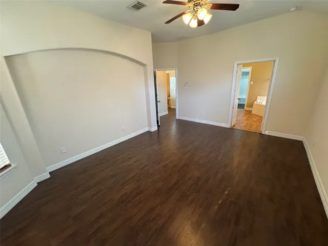a view of an empty room with chandelier fan and wooden floor