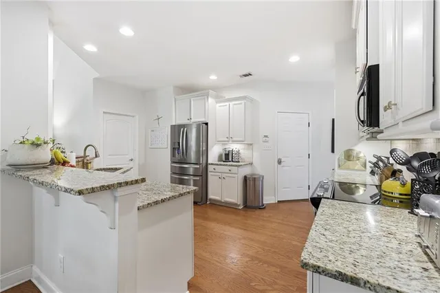 a kitchen with granite countertop a sink stainless steel appliances and white cabinets
